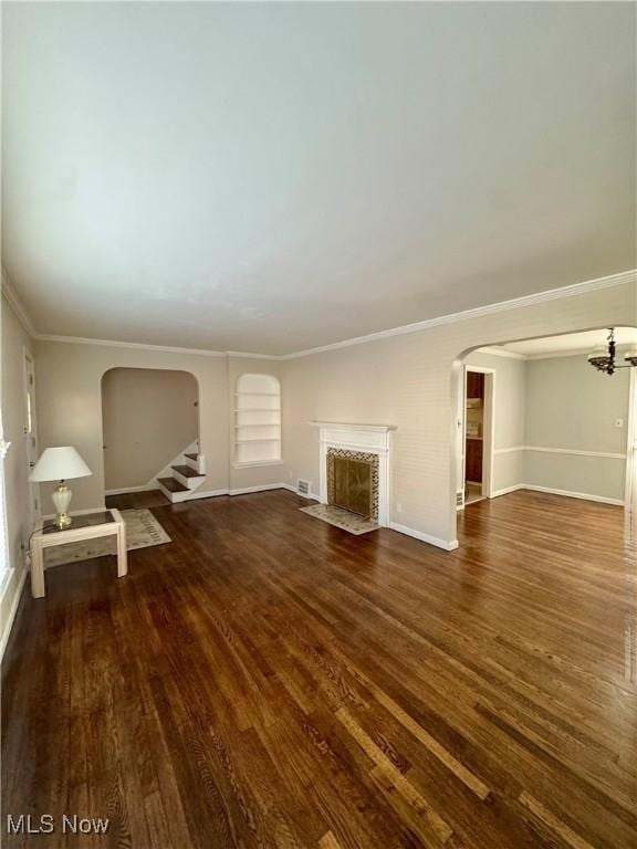 unfurnished living room featuring stairs, arched walkways, dark wood finished floors, and a premium fireplace