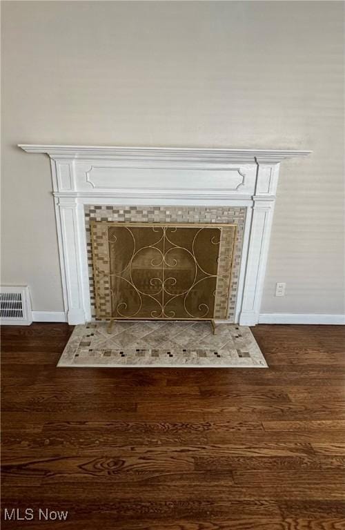 interior details with a fireplace, wood finished floors, visible vents, and baseboards