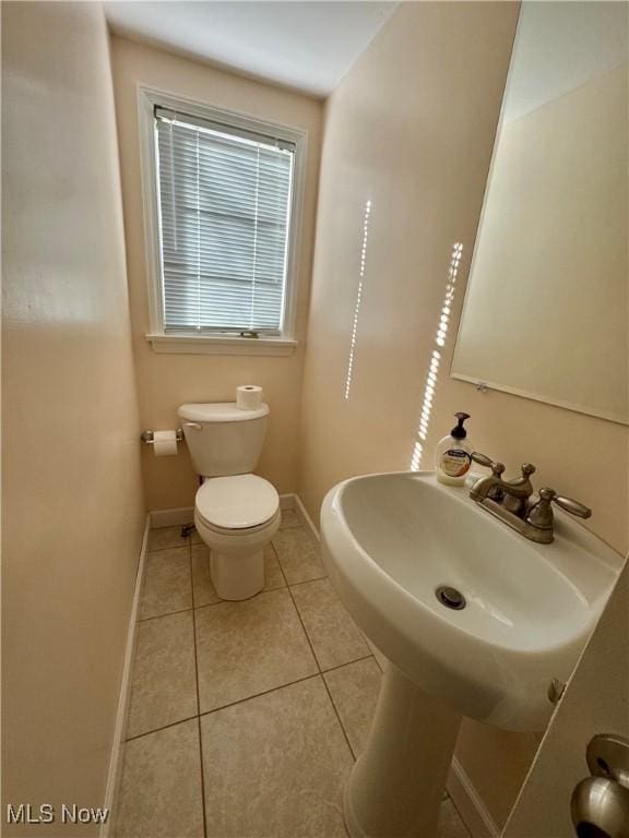 half bathroom featuring baseboards, toilet, and tile patterned floors