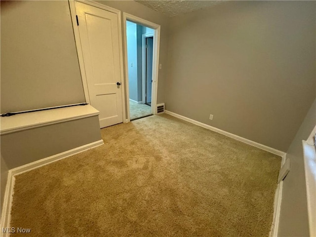 unfurnished bedroom with a textured ceiling, carpet, visible vents, and baseboards