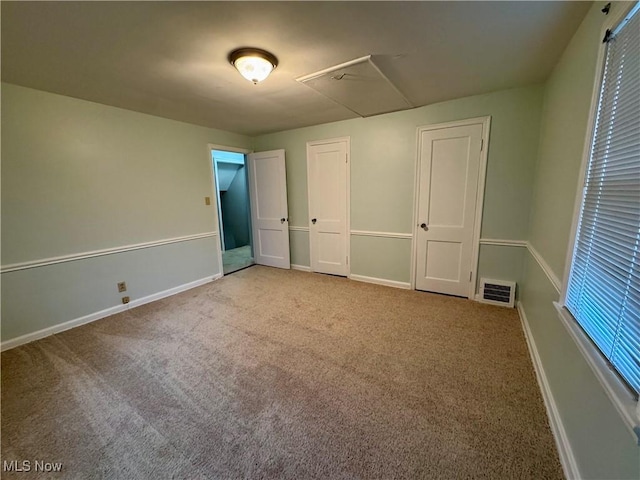 unfurnished bedroom with carpet, visible vents, and baseboards