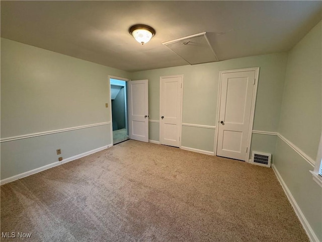 unfurnished bedroom with carpet floors, baseboards, and visible vents