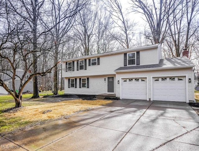 colonial home featuring a garage, a chimney, and concrete driveway