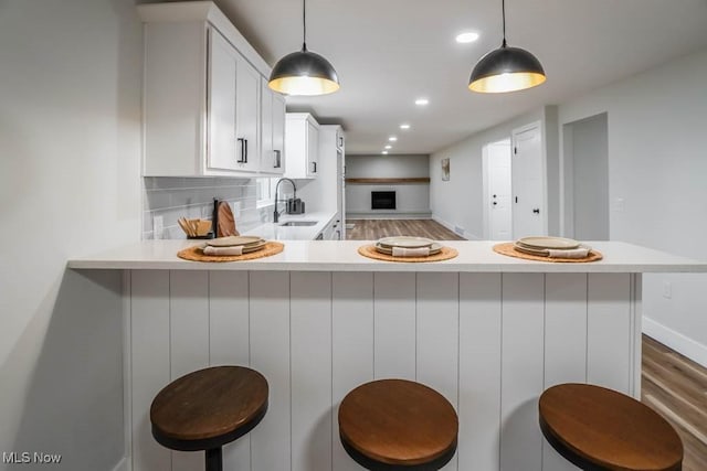 kitchen with tasteful backsplash, white cabinetry, light countertops, and a sink