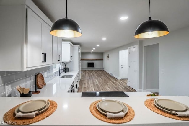 kitchen featuring white cabinets, light countertops, a sink, and backsplash