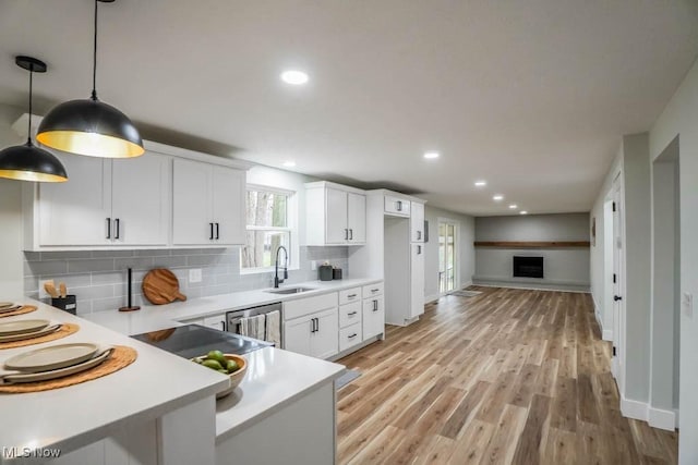 kitchen featuring tasteful backsplash, light countertops, light wood-style flooring, white cabinets, and a sink