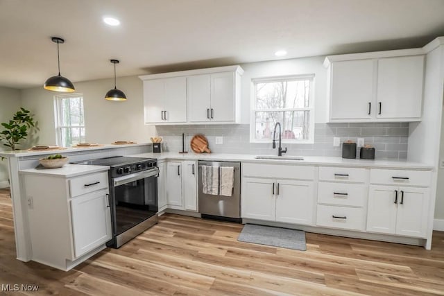 kitchen with electric range oven, a peninsula, stainless steel dishwasher, white cabinetry, and a sink