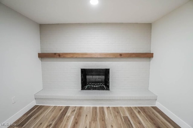 details with a brick fireplace, wood finished floors, and baseboards