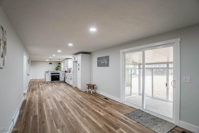 unfurnished living room with baseboards, recessed lighting, and light wood-style floors