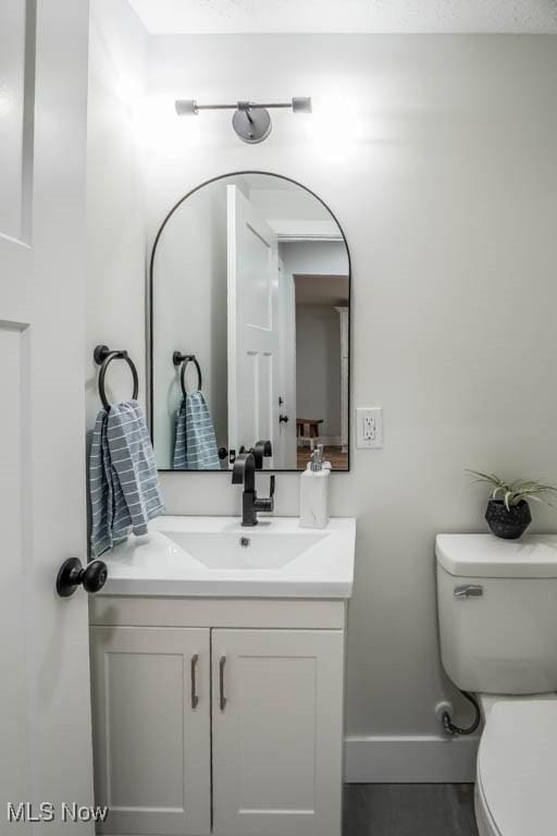 bathroom with vanity, toilet, and baseboards