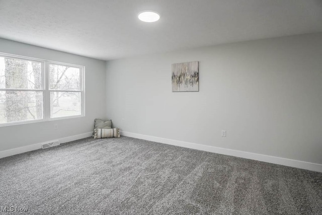 spare room featuring carpet flooring, visible vents, and baseboards