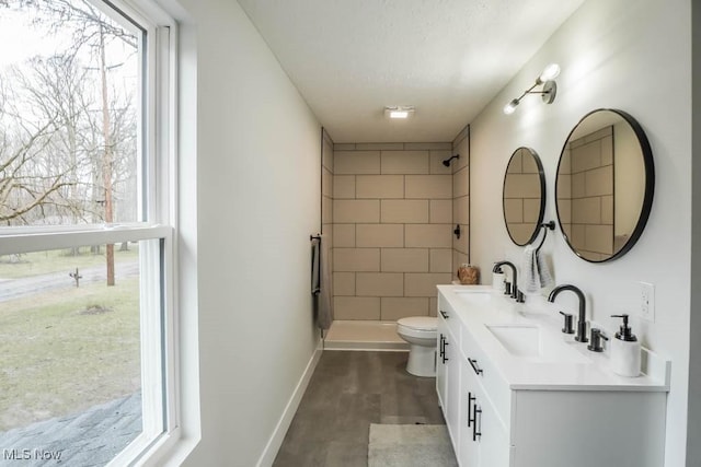 bathroom featuring a sink, a tile shower, and toilet