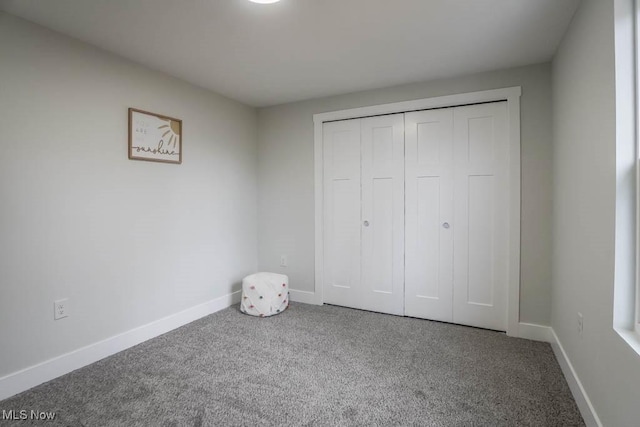 unfurnished bedroom with carpet, a closet, and baseboards