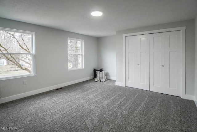 unfurnished bedroom featuring visible vents, a closet, baseboards, and carpet flooring