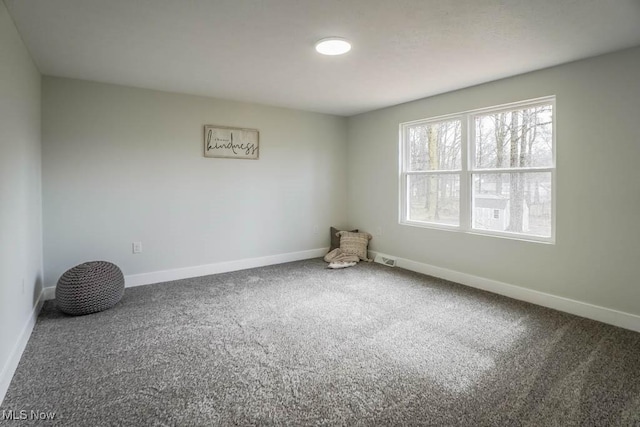 unfurnished room featuring carpet and baseboards