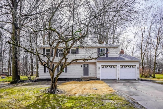 traditional-style home featuring a garage, a chimney, and concrete driveway