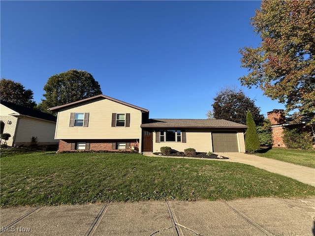 tri-level home with a front lawn, concrete driveway, brick siding, and an attached garage