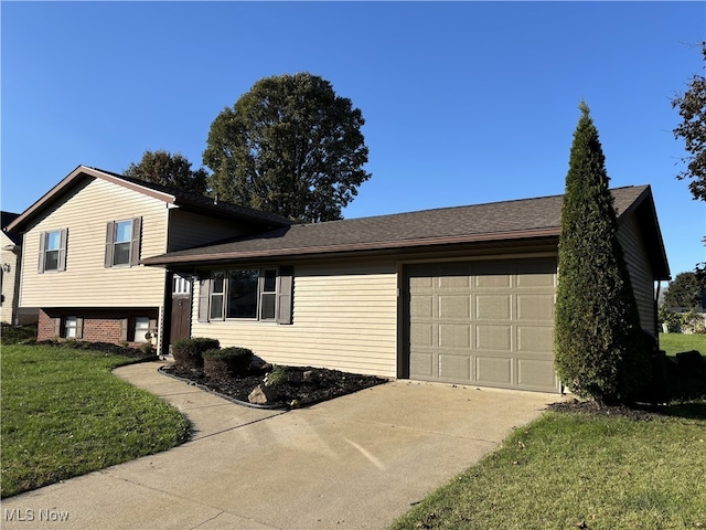 tri-level home featuring a garage, concrete driveway, and a front lawn