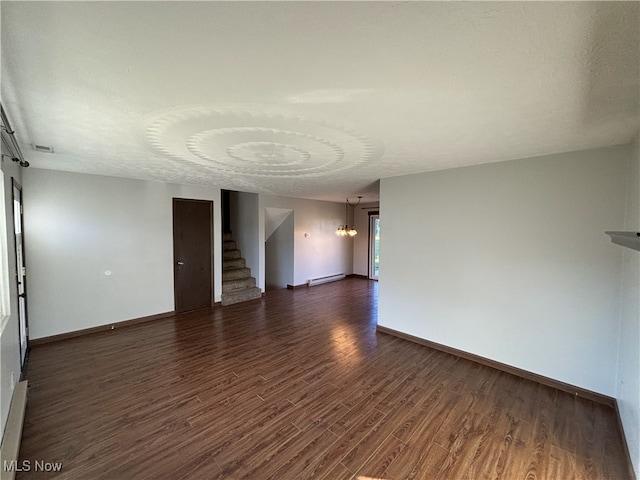 spare room with dark wood-type flooring, a baseboard radiator, stairway, and baseboards