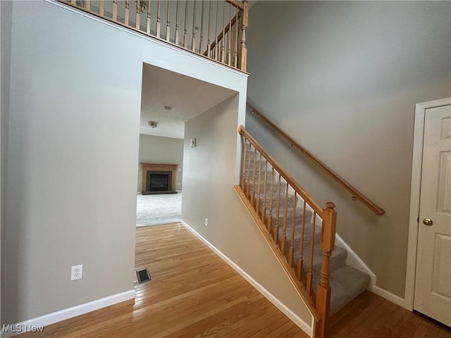 stairs featuring visible vents, a fireplace, baseboards, and wood finished floors