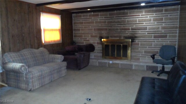 living room featuring beamed ceiling, a fireplace, and wooden walls