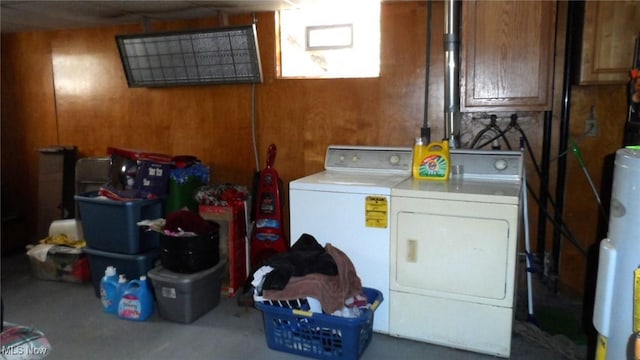 clothes washing area with washing machine and dryer, water heater, and wooden walls