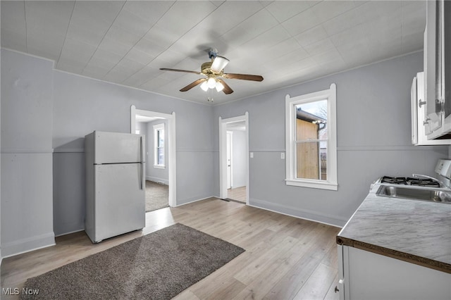 kitchen with ceiling fan, a sink, white cabinets, light wood-style floors, and freestanding refrigerator