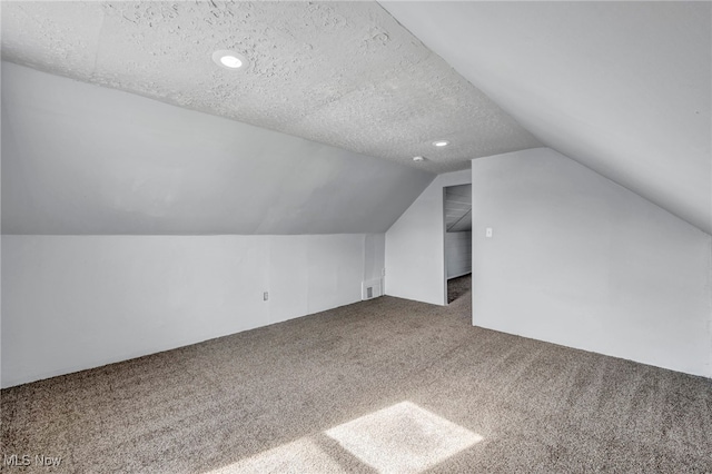 bonus room with lofted ceiling, carpet, visible vents, and a textured ceiling