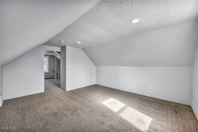 bonus room with carpet floors, lofted ceiling, and a textured ceiling