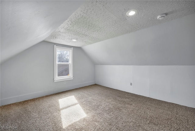 additional living space with a textured ceiling, carpet floors, and vaulted ceiling