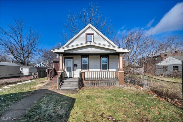 view of front of house featuring covered porch, fence, and a front lawn