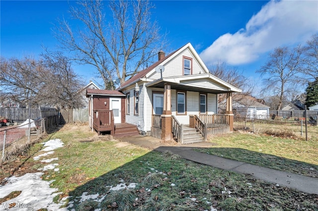 bungalow-style home with an outbuilding, a fenced backyard, covered porch, a chimney, and a front yard