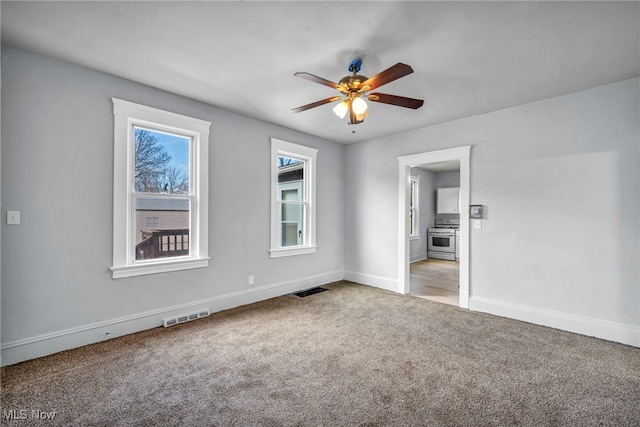 empty room with baseboards, ceiling fan, visible vents, and carpet flooring