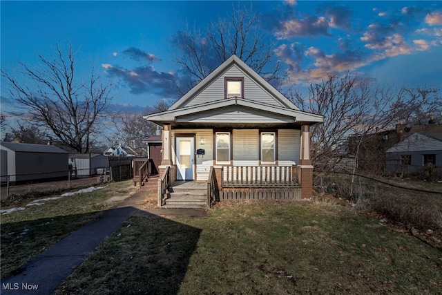 view of front of home featuring covered porch, a yard, and fence