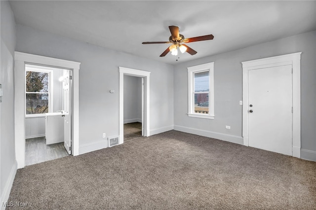 unfurnished bedroom featuring carpet, visible vents, ceiling fan, ensuite bath, and baseboards