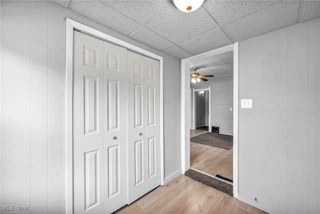 corridor featuring a paneled ceiling and light wood finished floors