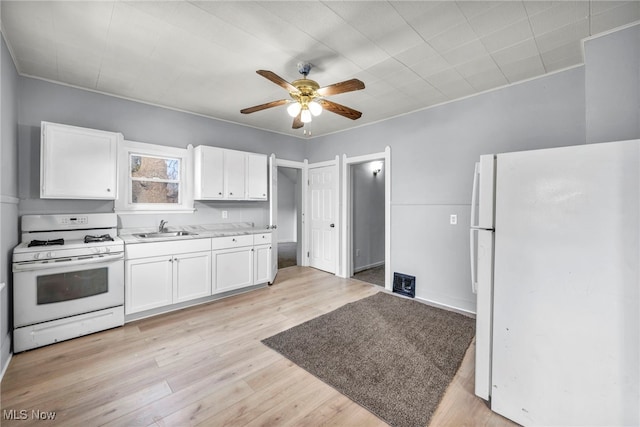 kitchen featuring white appliances, light wood-style flooring, light countertops, white cabinetry, and a sink