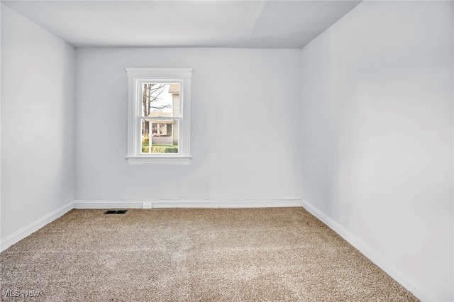 carpeted spare room featuring visible vents and baseboards