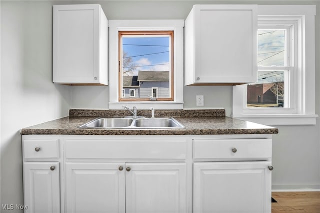 kitchen with dark countertops, a sink, and a healthy amount of sunlight