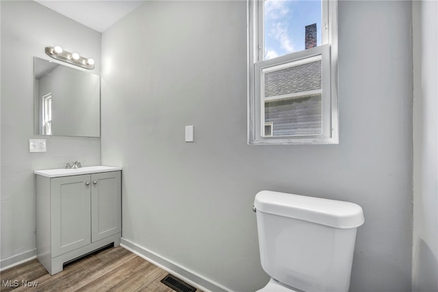 bathroom with baseboards, visible vents, toilet, wood finished floors, and vanity