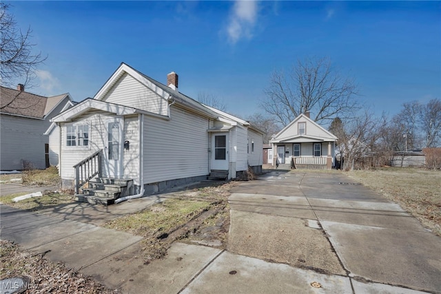 view of front of home with entry steps and a chimney