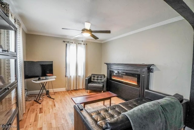 living area featuring wood-type flooring, baseboards, crown molding, and a glass covered fireplace