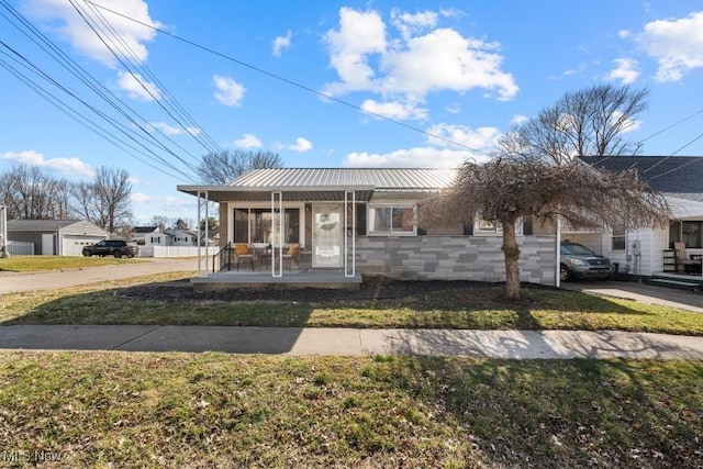 view of front of house featuring stone siding, a sunroom, metal roof, and a front lawn