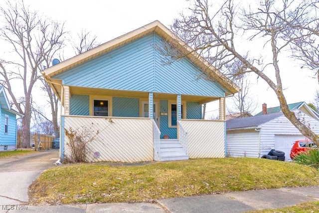 view of front of home featuring covered porch, a front lawn, and an outdoor structure