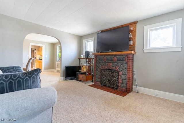 carpeted living area with arched walkways, a fireplace, and baseboards