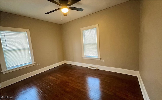 unfurnished room with dark wood-type flooring, visible vents, baseboards, and a ceiling fan