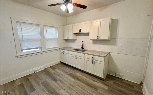 kitchen with dark wood-style floors, visible vents, a sink, and white cabinetry