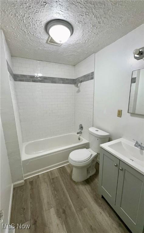 bathroom with a textured ceiling, bathtub / shower combination, toilet, wood finished floors, and vanity