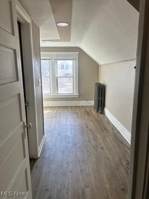 bonus room with lofted ceiling, radiator heating unit, wood finished floors, and baseboards