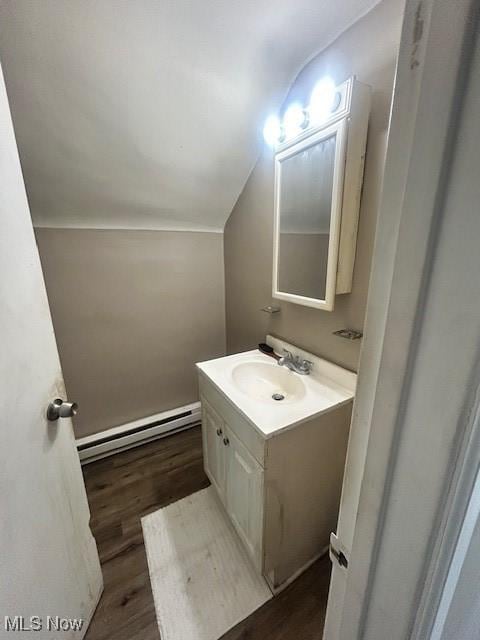 bathroom featuring lofted ceiling, a baseboard heating unit, wood finished floors, and vanity